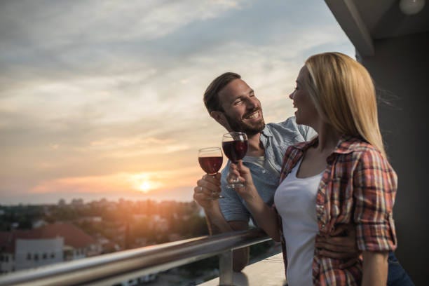Happy Couple Drinking Wine And Communicating On Penthouse Balcony At Sunset  Stock Photo - Download Image Now - iStock