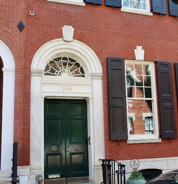 A green door in front of a brick building

Description automatically generated