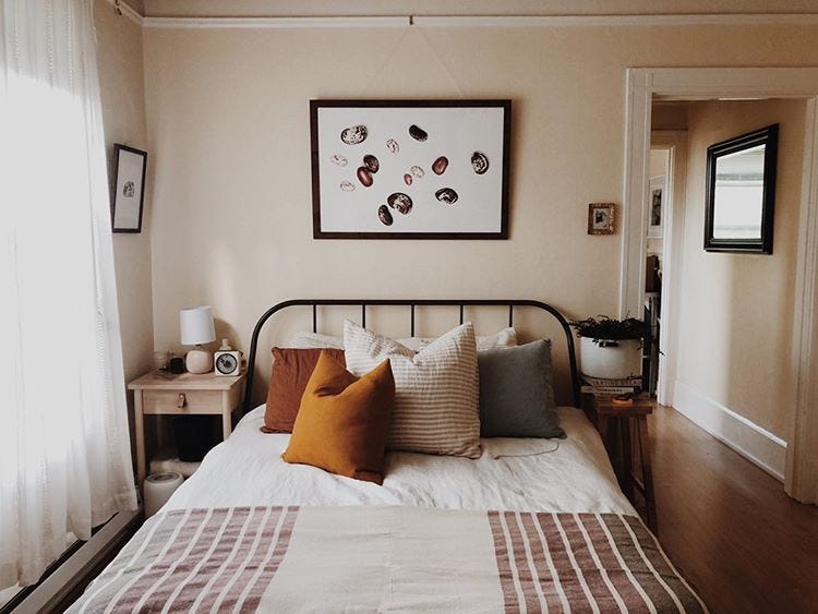 A photo of the bean painting hanging above a bed in a nicely lit bedroom