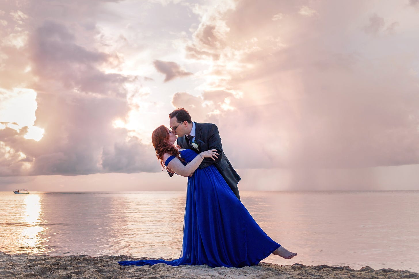 Bride and groom kissing as the sunsets on the beach