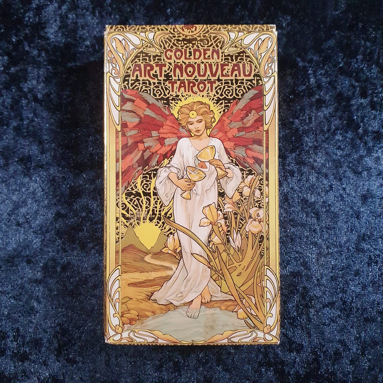 Golden Art Nouveau Tarot box photographed on dark blue velvet during Tarot DMs with Emma van Straaten, highlighting ornate Art Nouveau design, gilded detail, and vintage-inspired tarot aesthetics.
