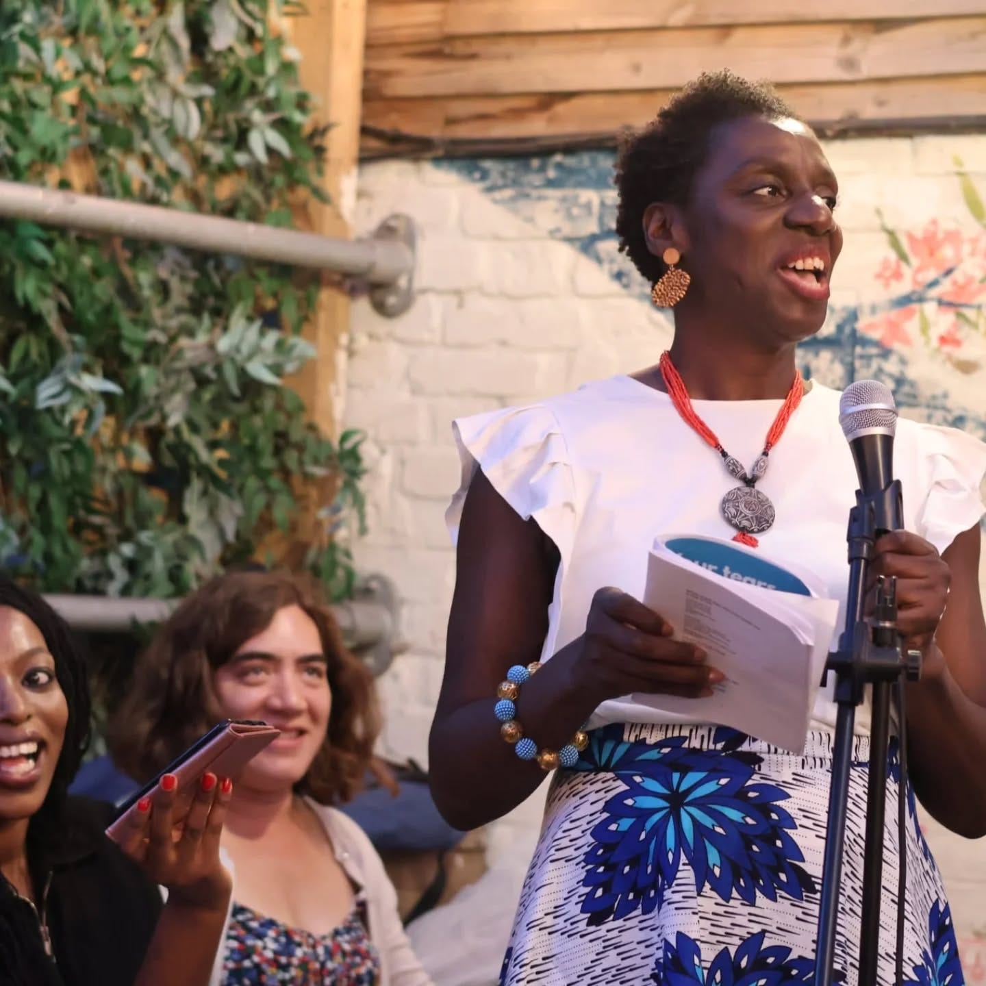 Adukeh the Poet in front of a microphone at her book lauanch