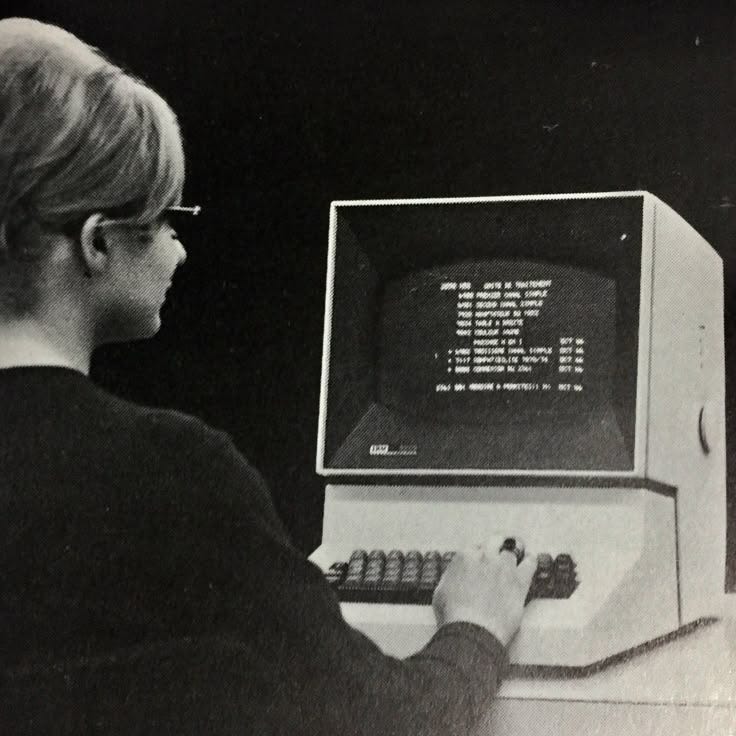 This may contain: a woman is using an old computer to read the code on it's screen