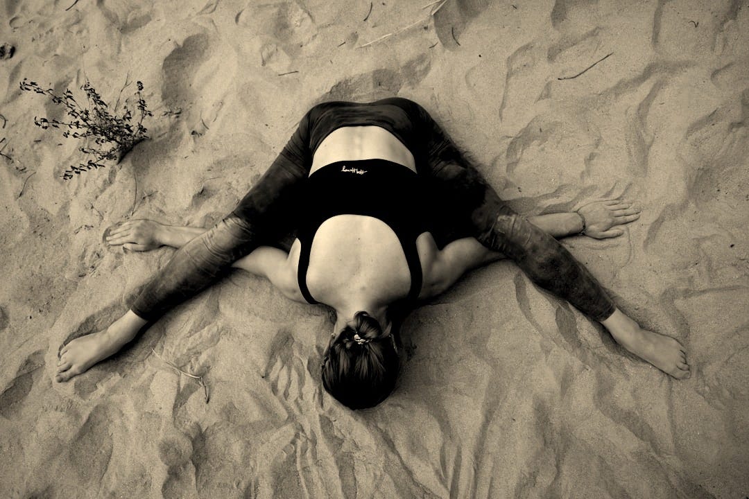 a woman laying on the sand with her back to the camera
