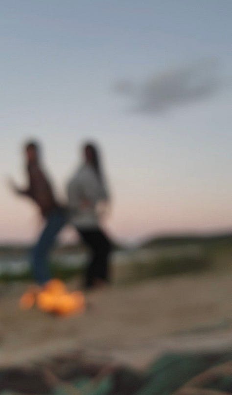 two women having fun behind a fire on the beach