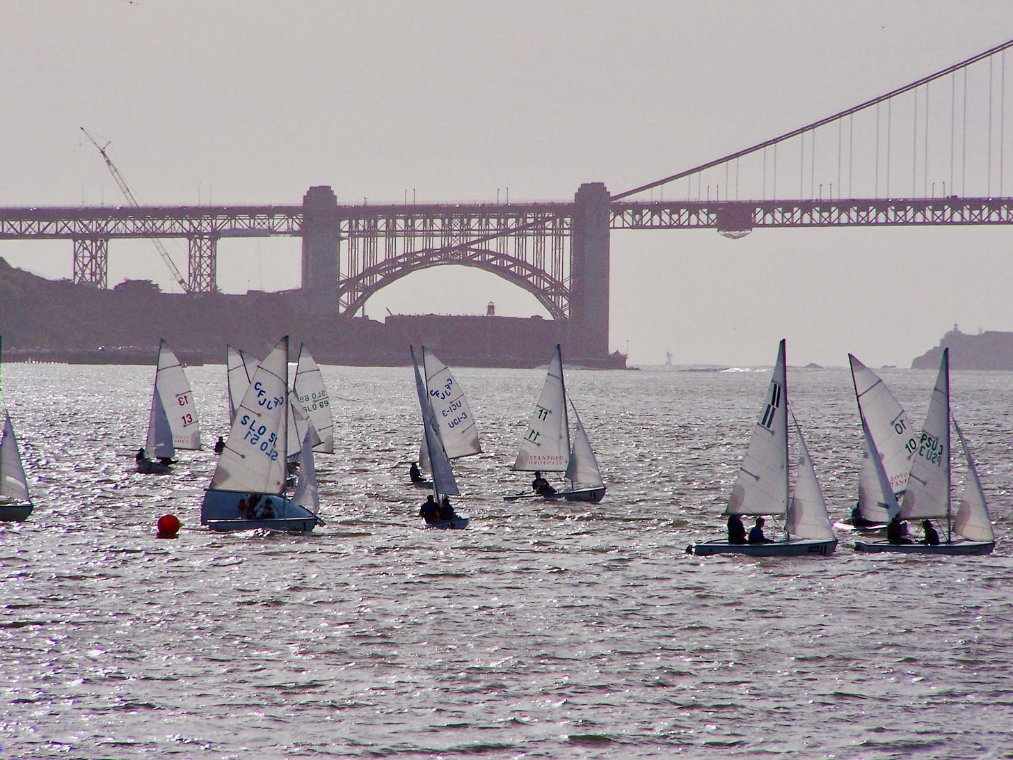 Ten sailboats in the foreground with a muted Golden Gate Bridge in the background
