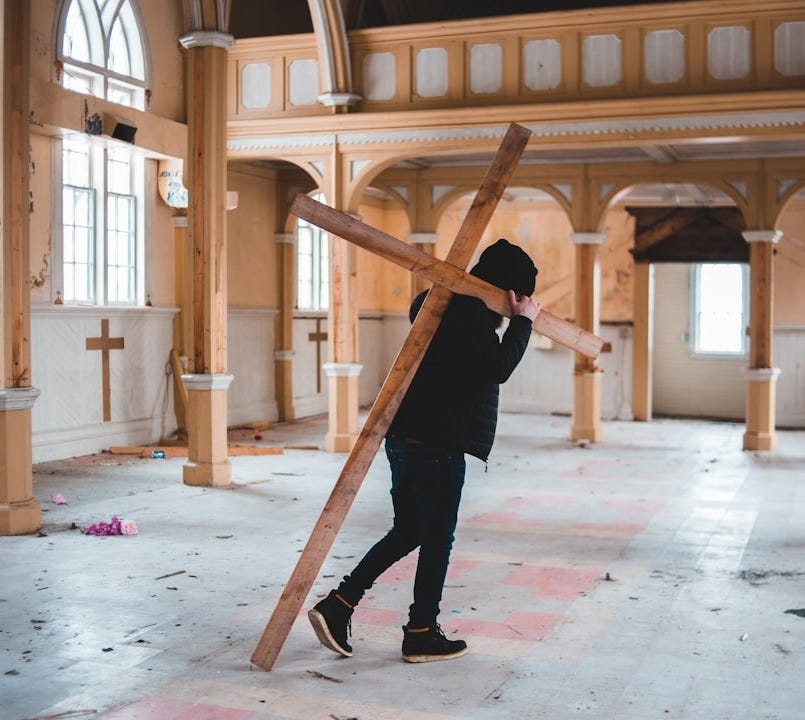 man in black jacket and black pants holding brown wooden stick