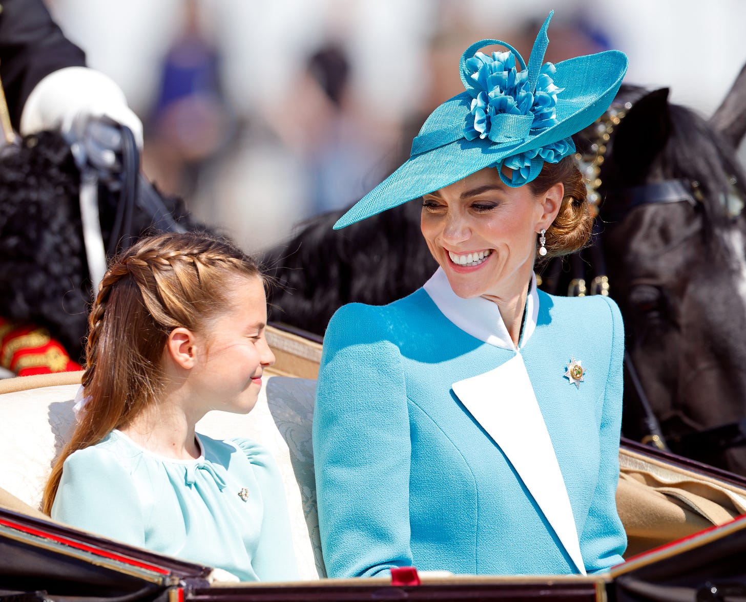 Princess Catherine wearing blue, smiling at Princess Charlotte wearing blue