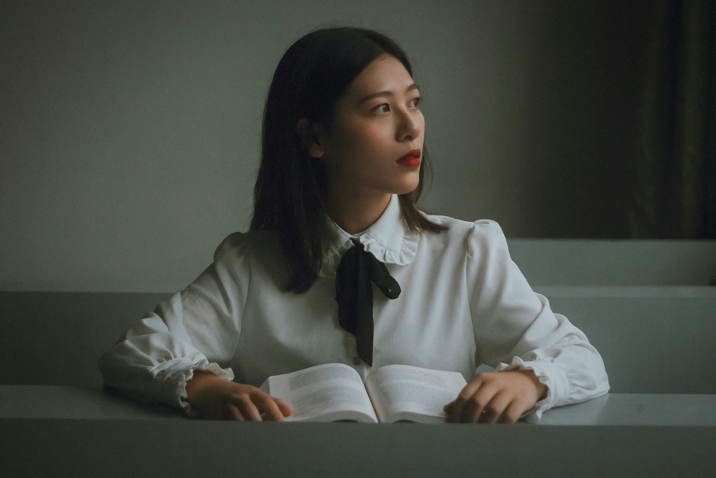 A woman sits at her desk reading, but wonders about becoming a writer