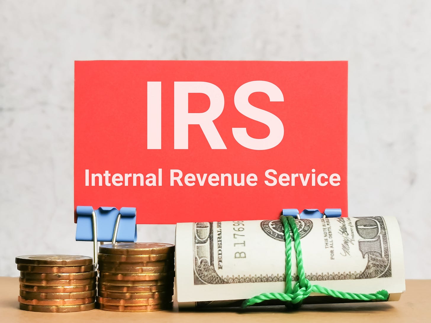 IRS sign with rolled U.S. dollar bills and coins, symbolizing quarterly tax payments.
