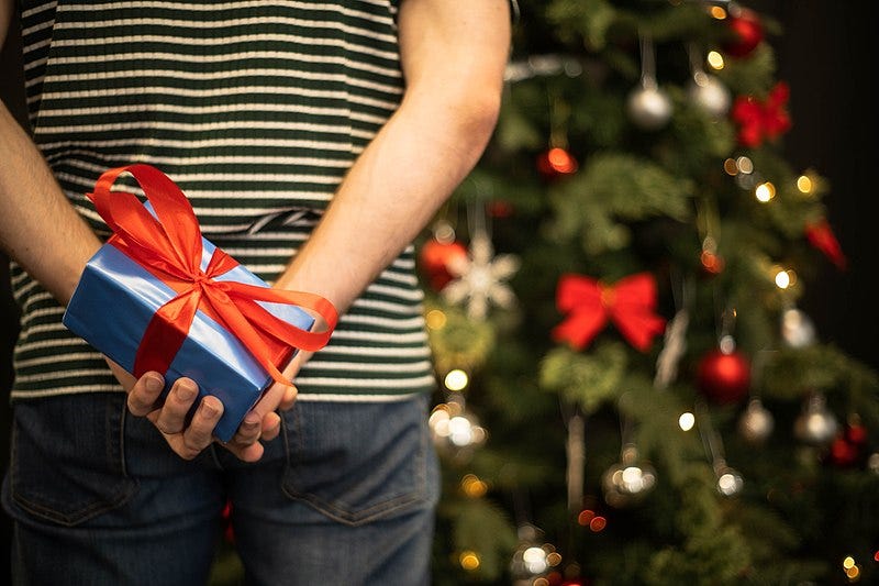 A person holding a present behind their back

Description automatically generated