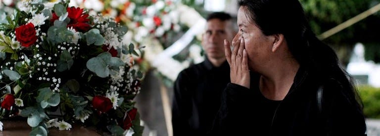 A relative of Silverio Villegas Gonzalez, 38, a man from Michoacan who was fatally shot by a U.S. Immigration and Customs Enforcement (ICE) agent in Franklin Park, Illinois, shortly after dropping off his two children at a nearby elementary school and daycare, wipes away tears while standing next to his casket during a tribute by local authorities in Irimbo, Mexico, September 26, 2025. REUTERS/Ivan Arias
