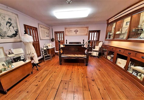 A gallery at the Country Doctor Museum set up as a "sick room" showing a bed and other articles that might be found, including a flower-painted pitcher and basin for washing up, and Mrs. Winslow's medicine advertisement.