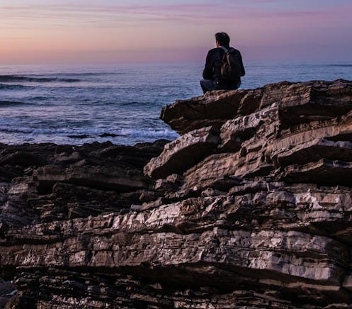 person sitting on cliff