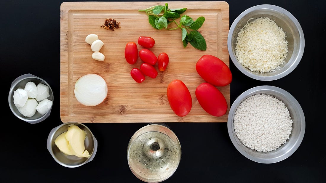 Foto dos ingredientes do risoto caprese organizados sobre uma bancada preta.