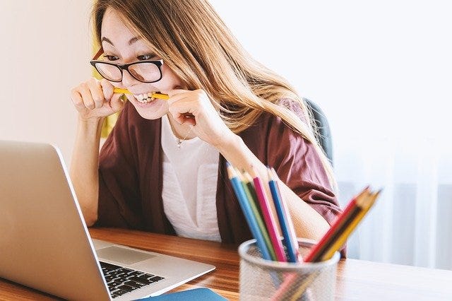 A stressed young woman hunched over a laptop computer. A stressed young woman hunched over a laptop computer.