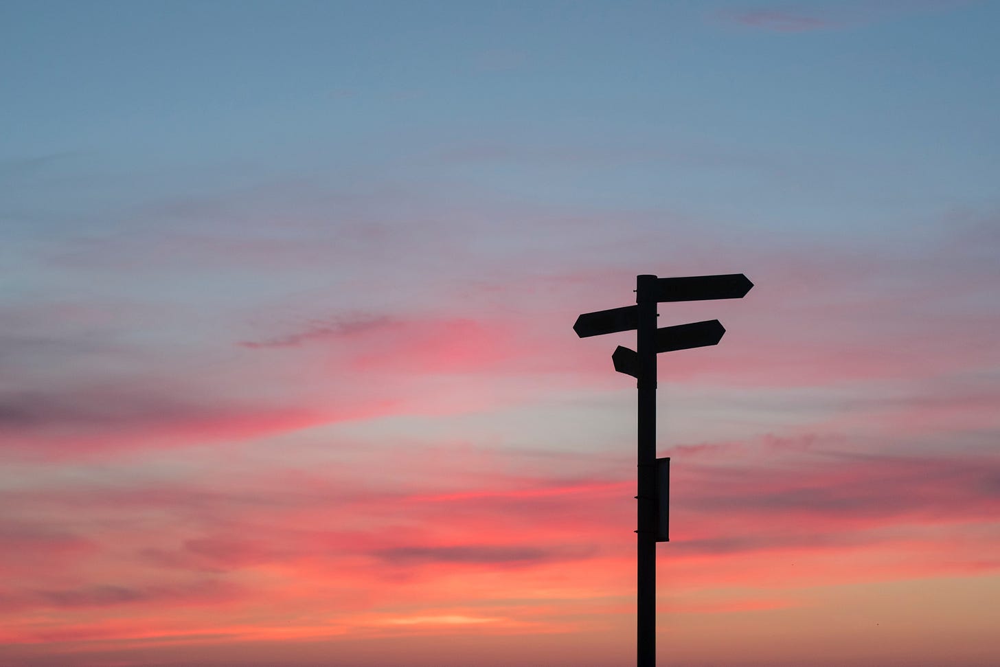 sunset with silhouette of road signs at intersection