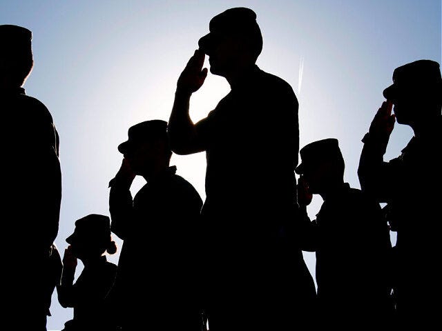 Several soldiers salute the flag at sunset during a military exercise. Army, Marines and Air Force were represented at the ceremony.