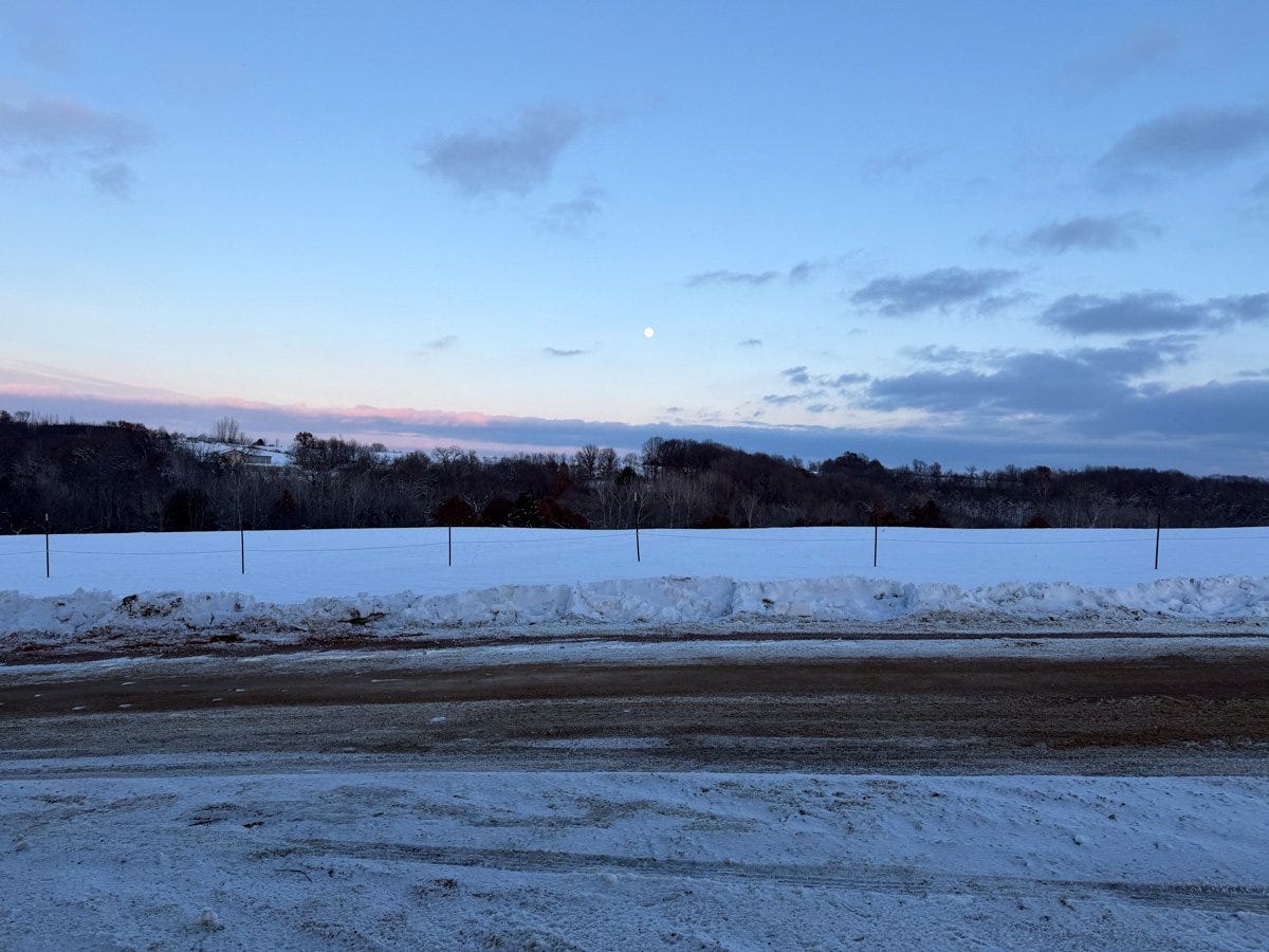 the moon rising over a snowy field