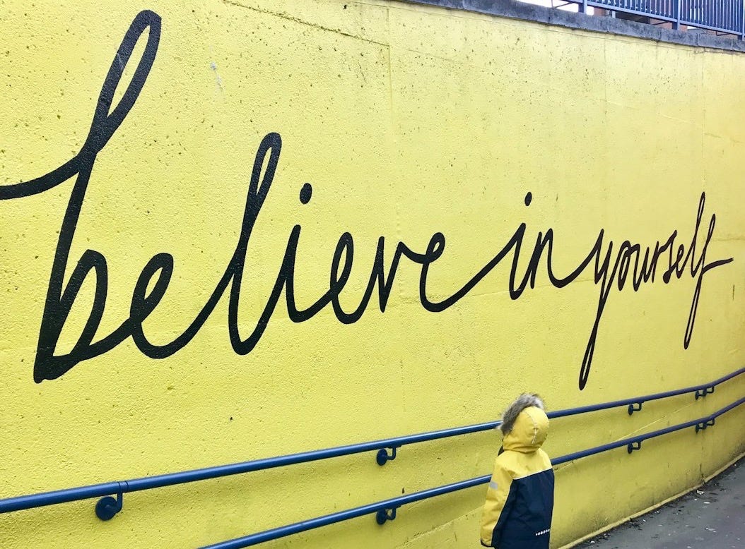 toddler looking at believe in yourself graffiti