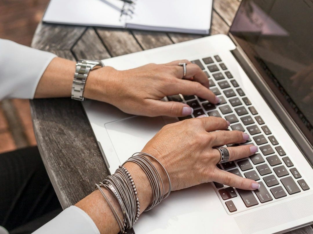 person typing on MacBook Pro on brown wooden table during daytime photo