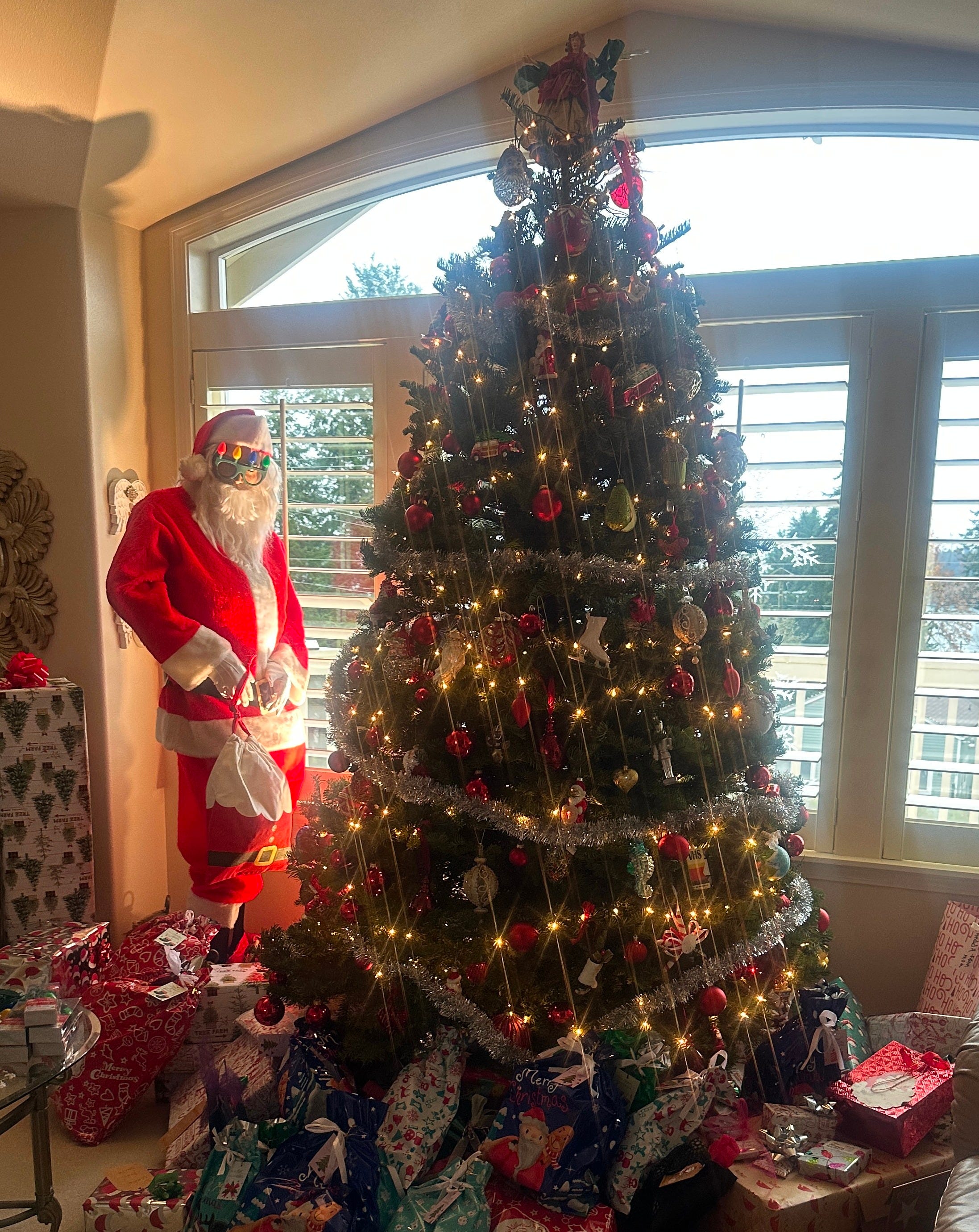 A mannequin dressed as Santa and a decorated Christmas tree with presents