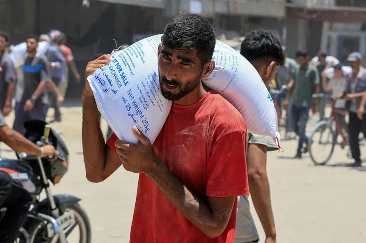 A Palestinian carries a sack of flour as people gather to receive aid supplies in Khan Younis, in the southern Gaza Strip, June 26, 2025. REUTERS/Hatem Khaled