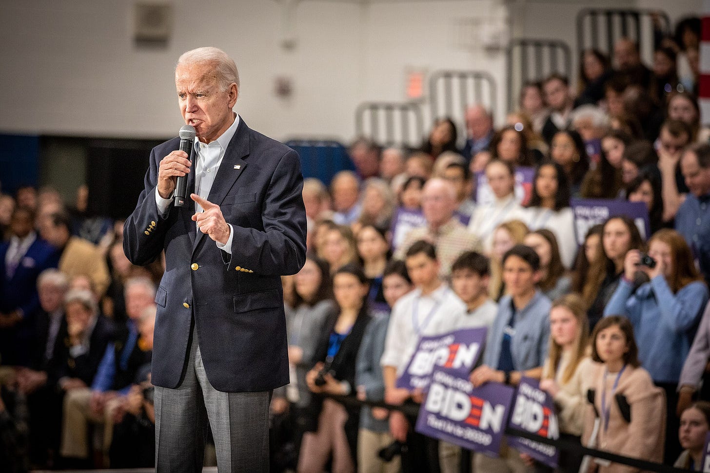 Photo of Biden holding a microphone, with a crowd in the background