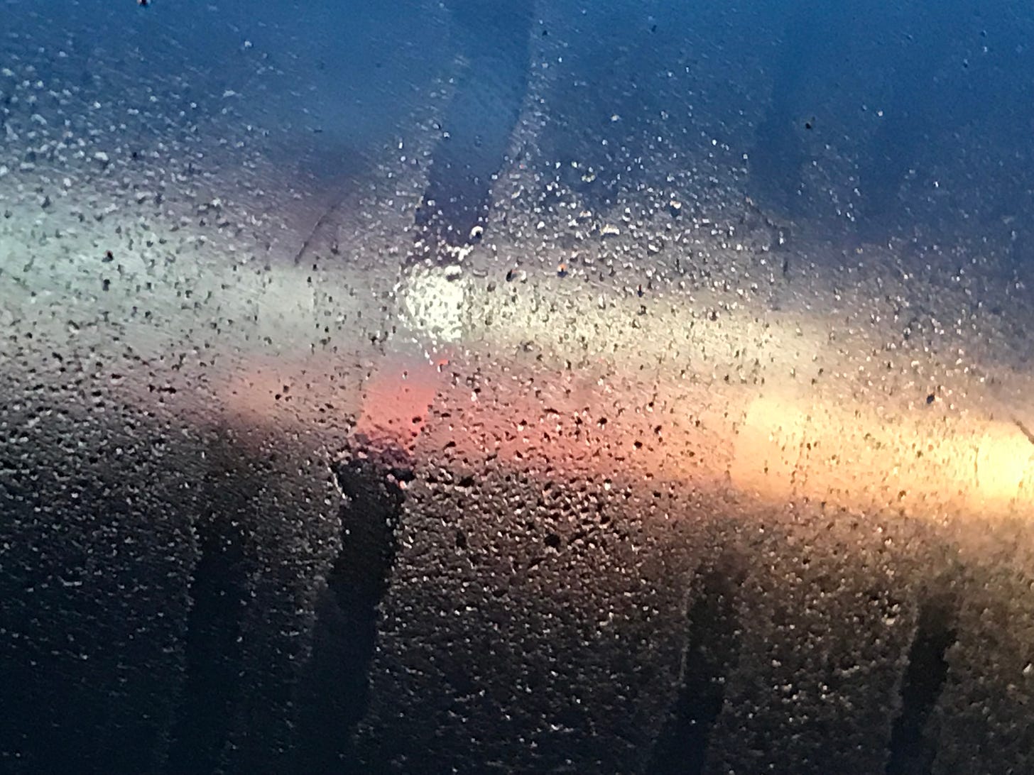 Sunset reflected on a rain-splattered windowpane