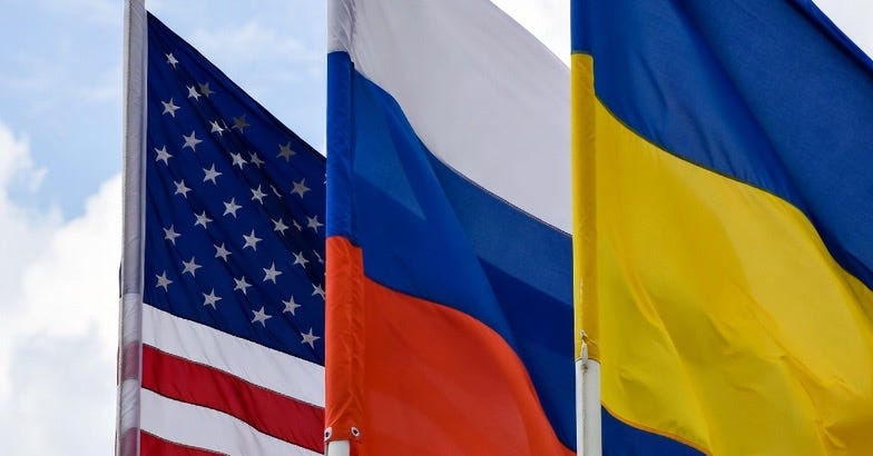 A photograph of the American, Russian, and Ukrainian flags displayed side by side against a clear sky.