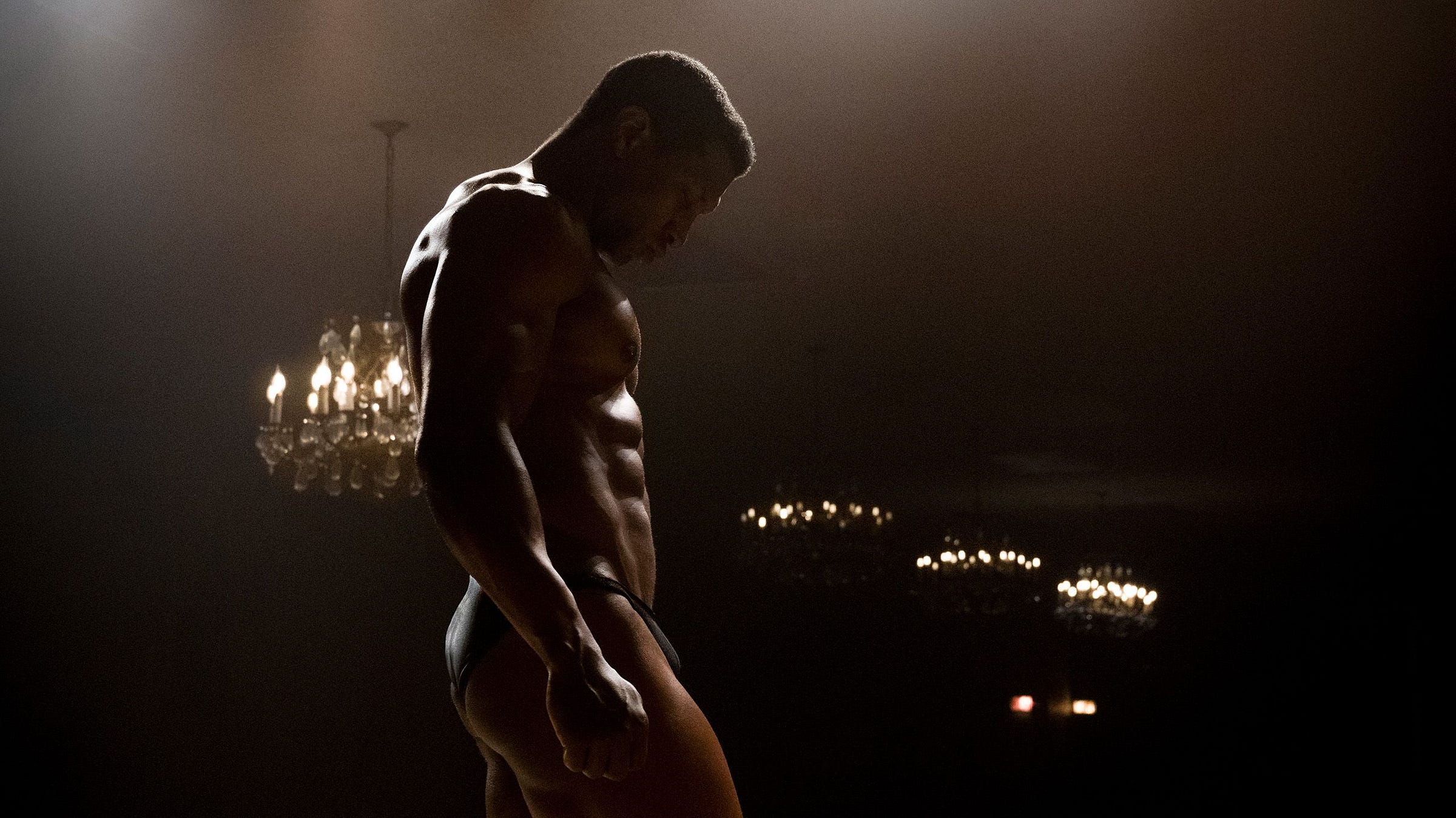 Jonathan Majors posing as Killian Maddox on stage at a bodybuilder competition