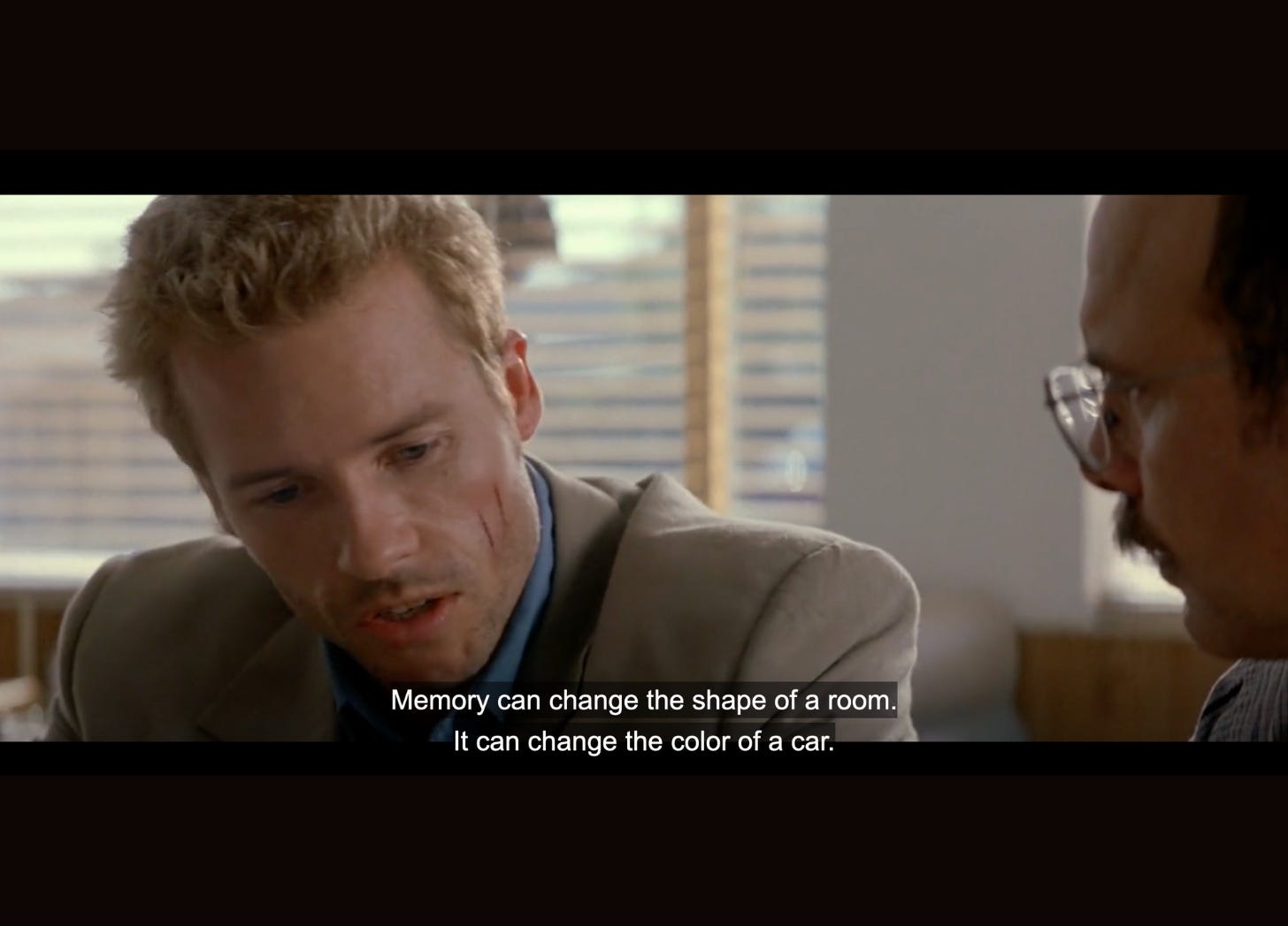 Scene from Memento with the main character saying: "Memory can change the shape of a room. It can change the color of a car."