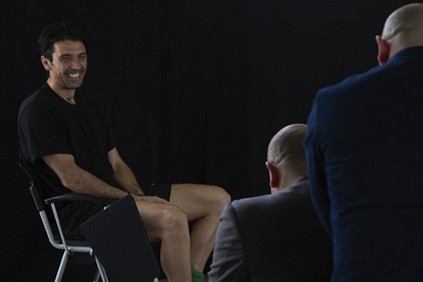 Gianluigi Buffon during a filmed interview on May 12, 2012: shown smiling, speaking, in profile, gesturing with emphasis, and seated against a black background.