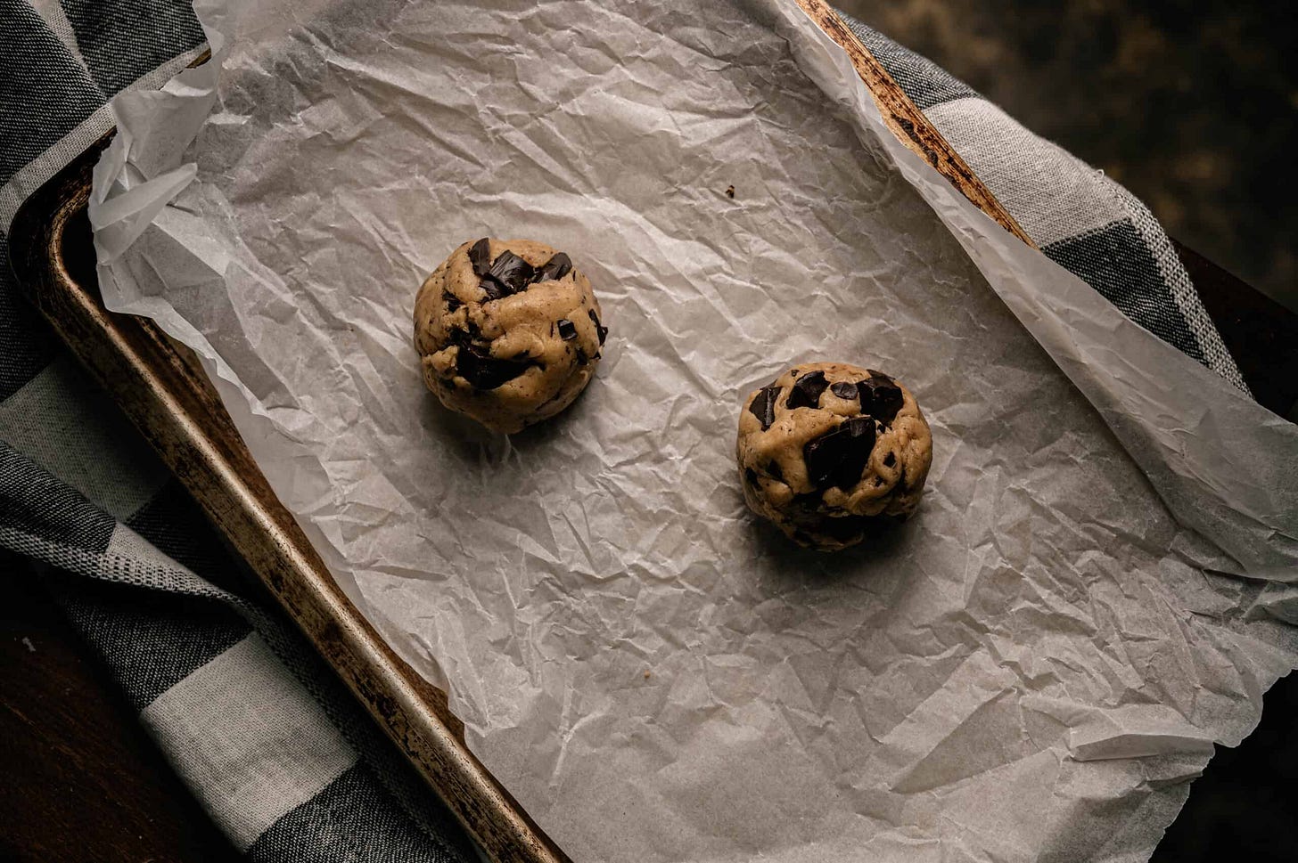 small batch chocolate chip cookies recipe cookie dough balls on a baking sheet lined with parchment paper to back