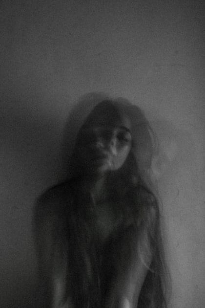 This may contain: a woman with long hair standing in front of a wall