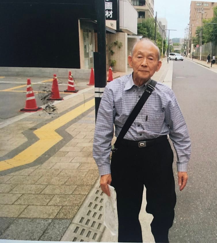 An elderly Japanese man walking down a street. An elderly Japanese man walking down a street.