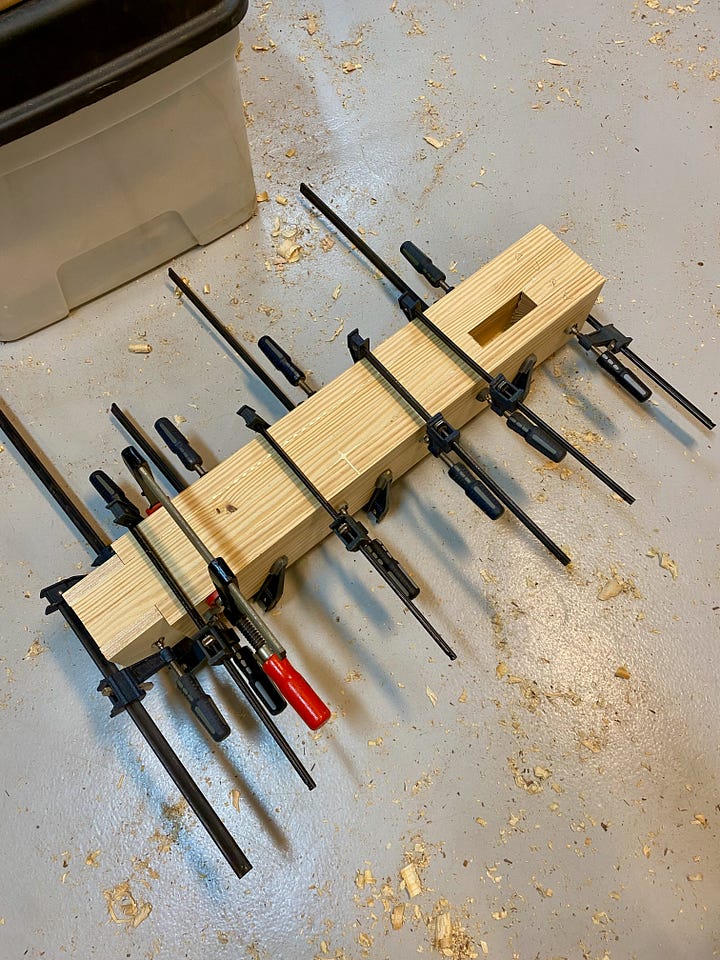 Chiseling a notch in a leg, gluing and clamping a leg, and then cutting a second notch with a chisel.