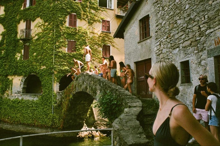 This may contain: some people are standing on the side of a building and one person is walking over a bridge This may contain: some people are standing on the side of a building and one person is walking over a bridge