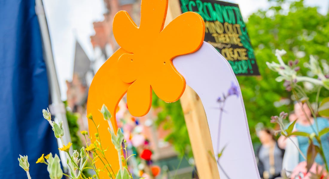 An orange and purple arch with flowers growing in front of it An orange and purple arch with flowers growing in front of it