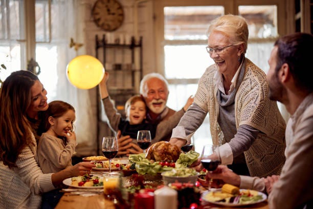 Happy senior woman serving a meal to her family in dining room. Happy mature woman serving food to her family during Thanksgiving meal at dining table. happy people eating at home stock pictures, royalty-free photos & images