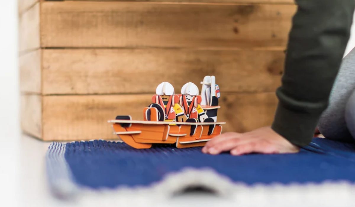RNLI Inshore Lifeboat Playset on a blue rug, with a wooden box behind