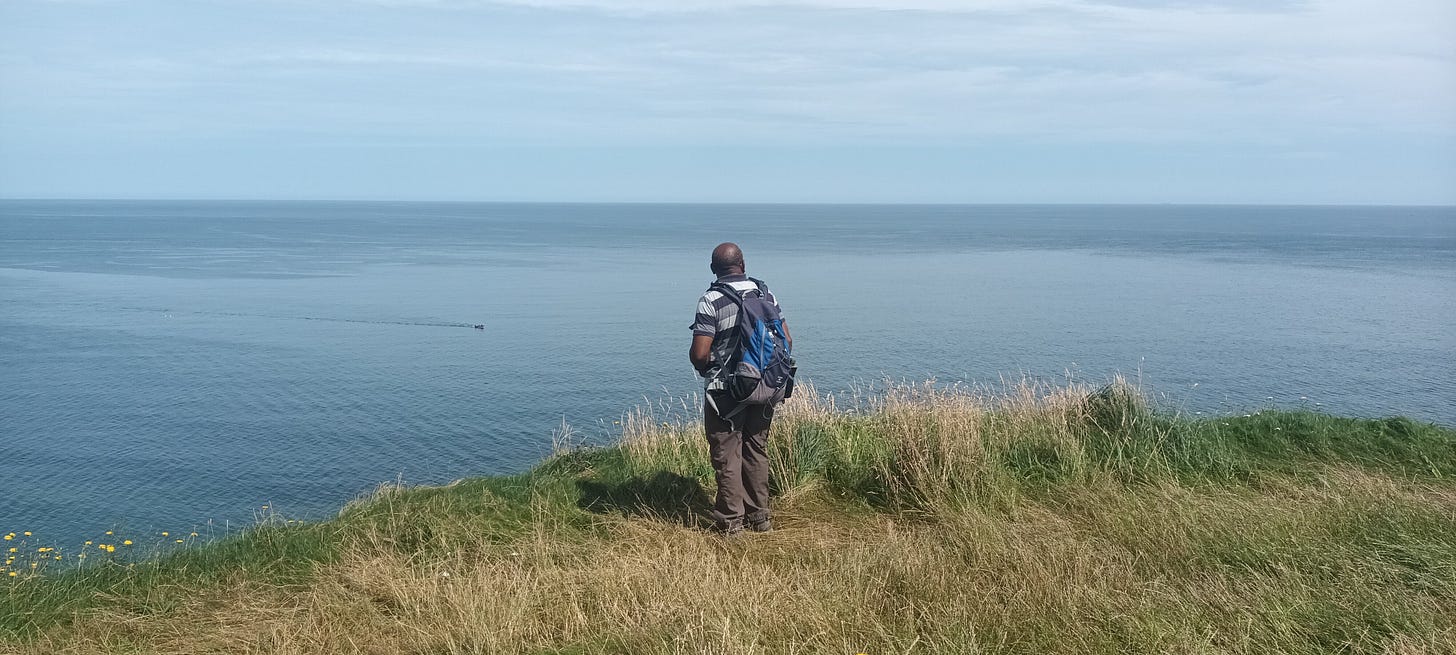 A man standing on the clifftops looking out to sea