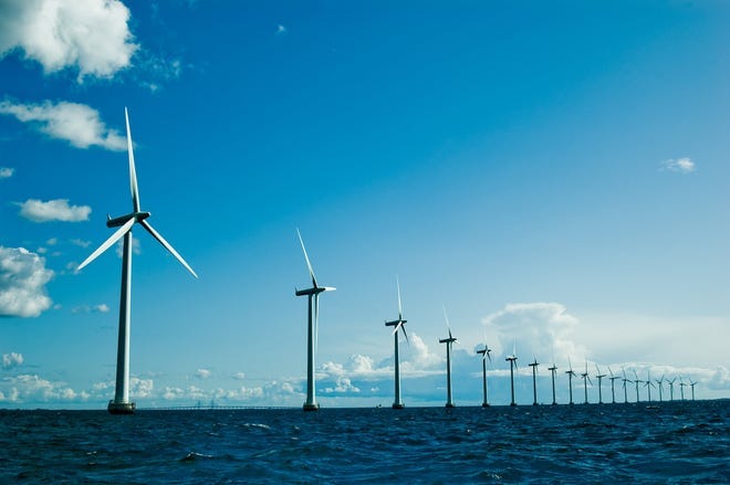 A long line of giant wind turbines in the ocean.