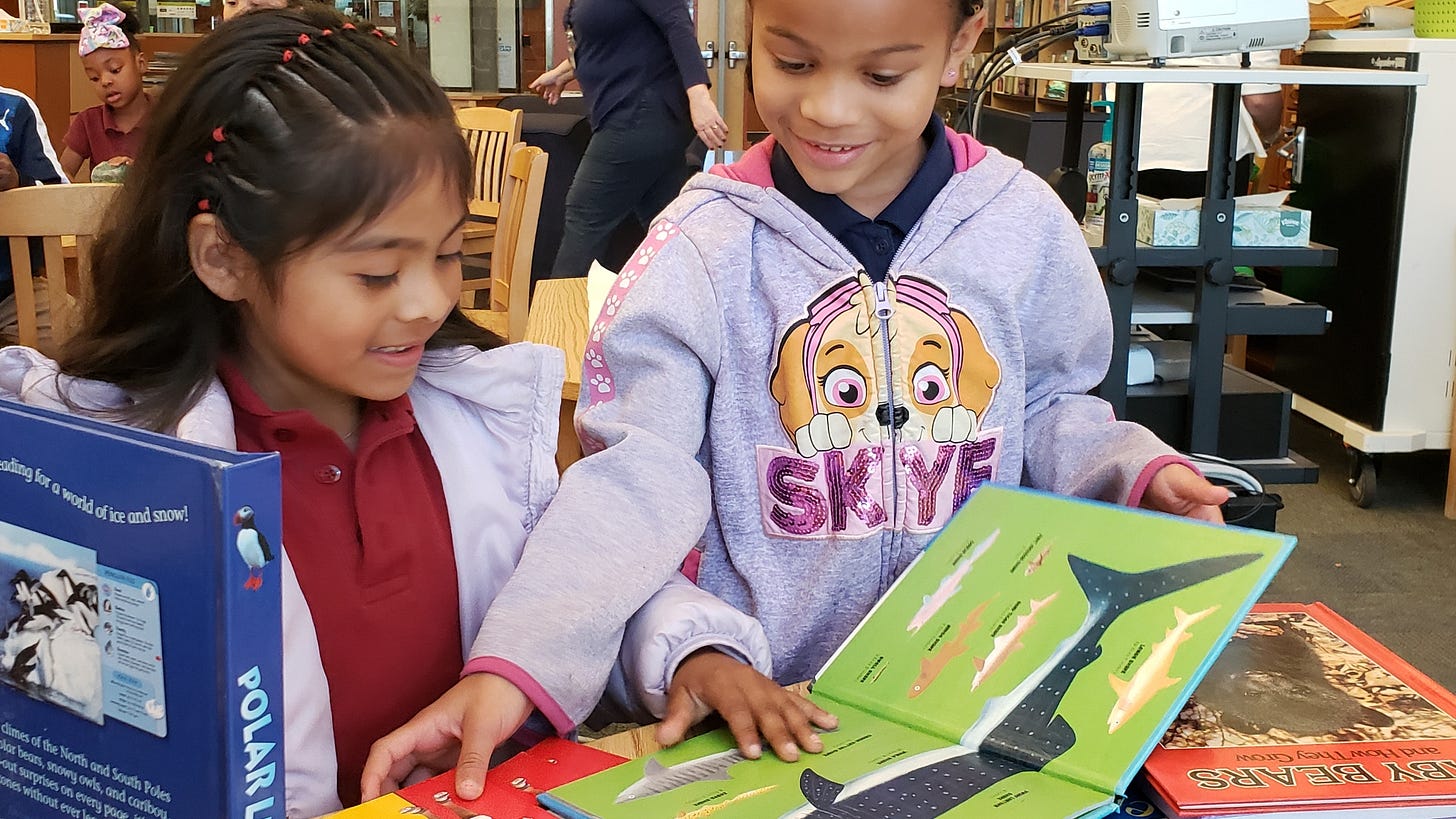 Kids looking through books that came from a book drive. Kids looking through books that came from a book drive.