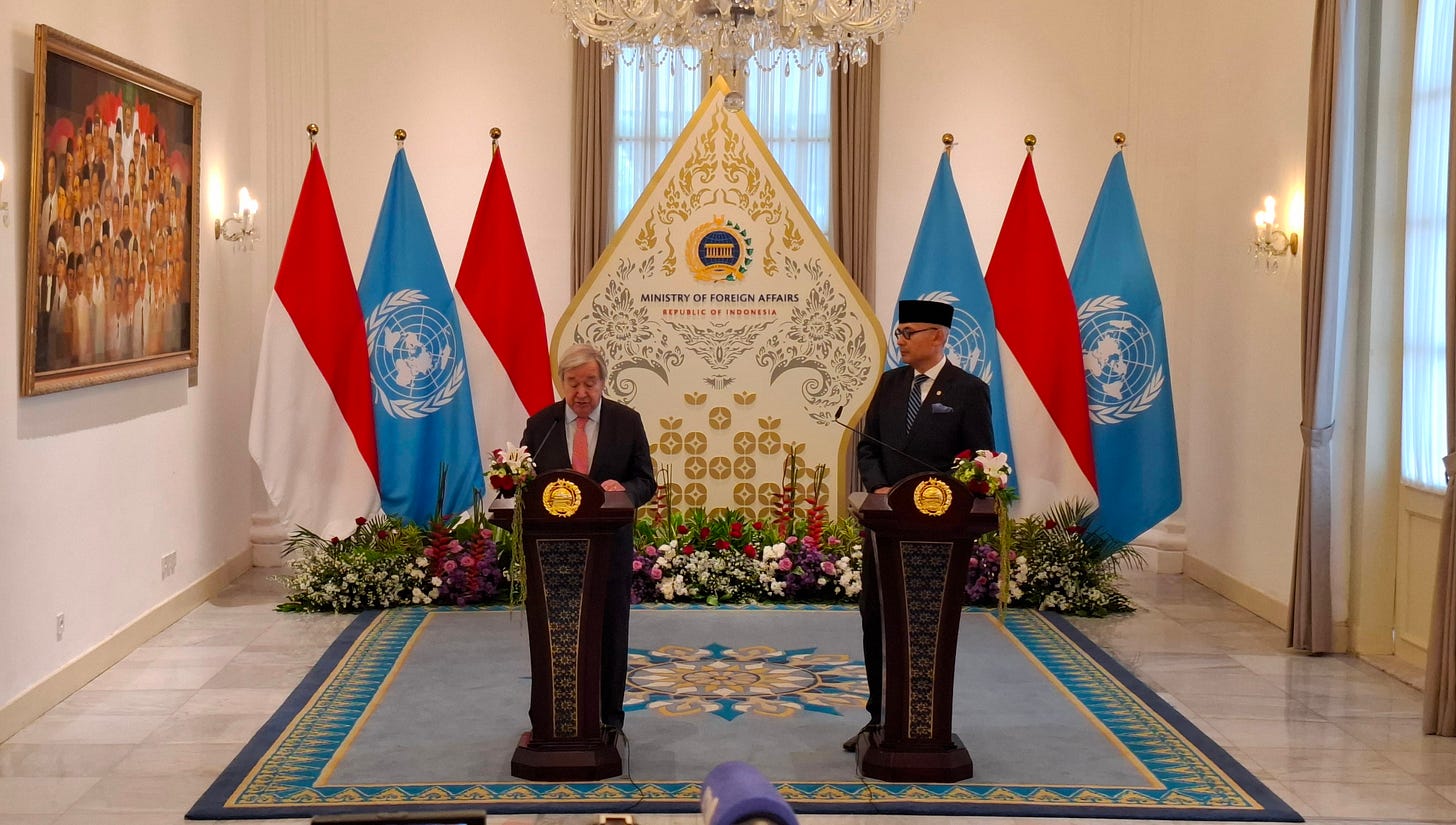 Two men stand behind a podium in front of the UN and Indonesian flags. On the left is UN Secretary-General António Guterres, and on the right is Indonesian Foreign Affairs Minister Arrmanatha Nasir. They hold a joint press briefing at the Pancasila Building in Jakarta on Monday (19 October), following the foreign policy talks.
