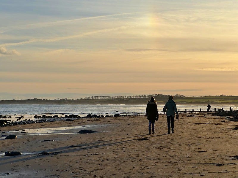 a couple on a beach walking into the sunset (author's own photo)