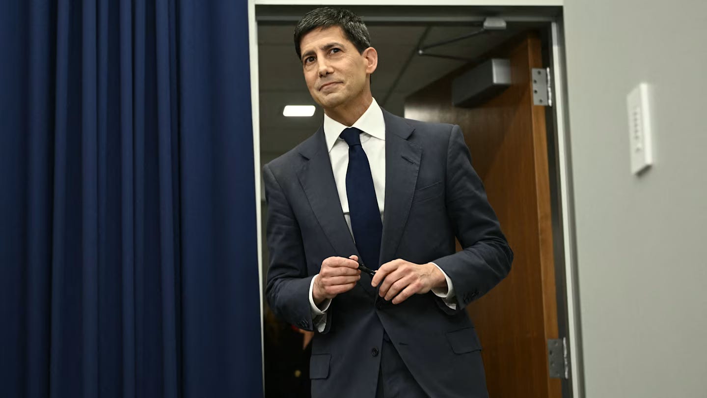 Kevin Warsh enters a room in a suit and tie, holding a pen, ahead of a press conference. Kevin Warsh enters a room in a suit and tie, holding a pen, ahead of a press conference.