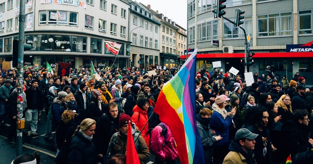 Crowd holding rainbow flag during a protest