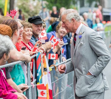 Le roi Charles III sourit à une foule derrière une barrière. Les membres de la foule tiennent un drapeau du Canada dans leurs mains. Le roi Charles III sourit à une foule derrière une barrière. Les membres de la foule tiennent un drapeau du Canada dans leurs mains.