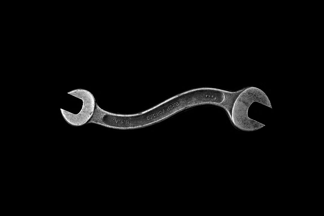 A serious portrait of a curved wrench on a black background A serious portrait of a curved wrench on a black background